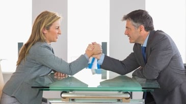 two competitors in business attire arm wrestling